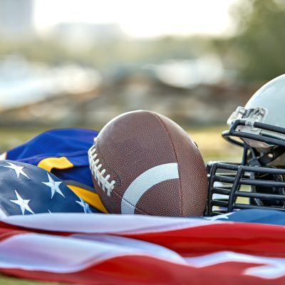 American football concept. American football equipment, helmet, ball close-up on the background of the American flag. Patriotism